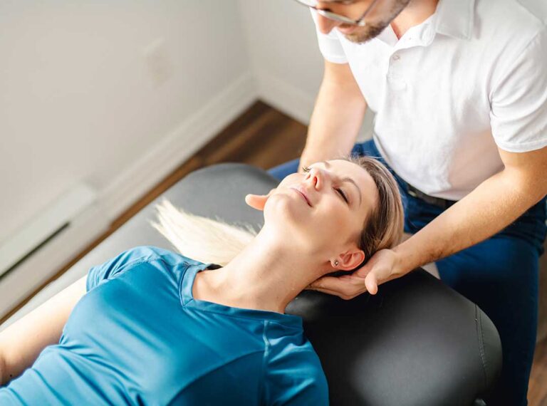 A pregnant person lying comfortably on a chiropractic adjustment table with supportive pillows.
